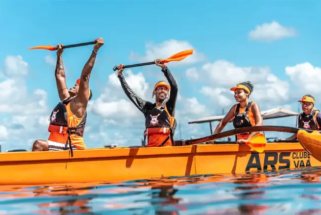 Equipe de atletas sincronizados remando juntos em uma canoa havaiana na Praia da Preguiça em Salvador